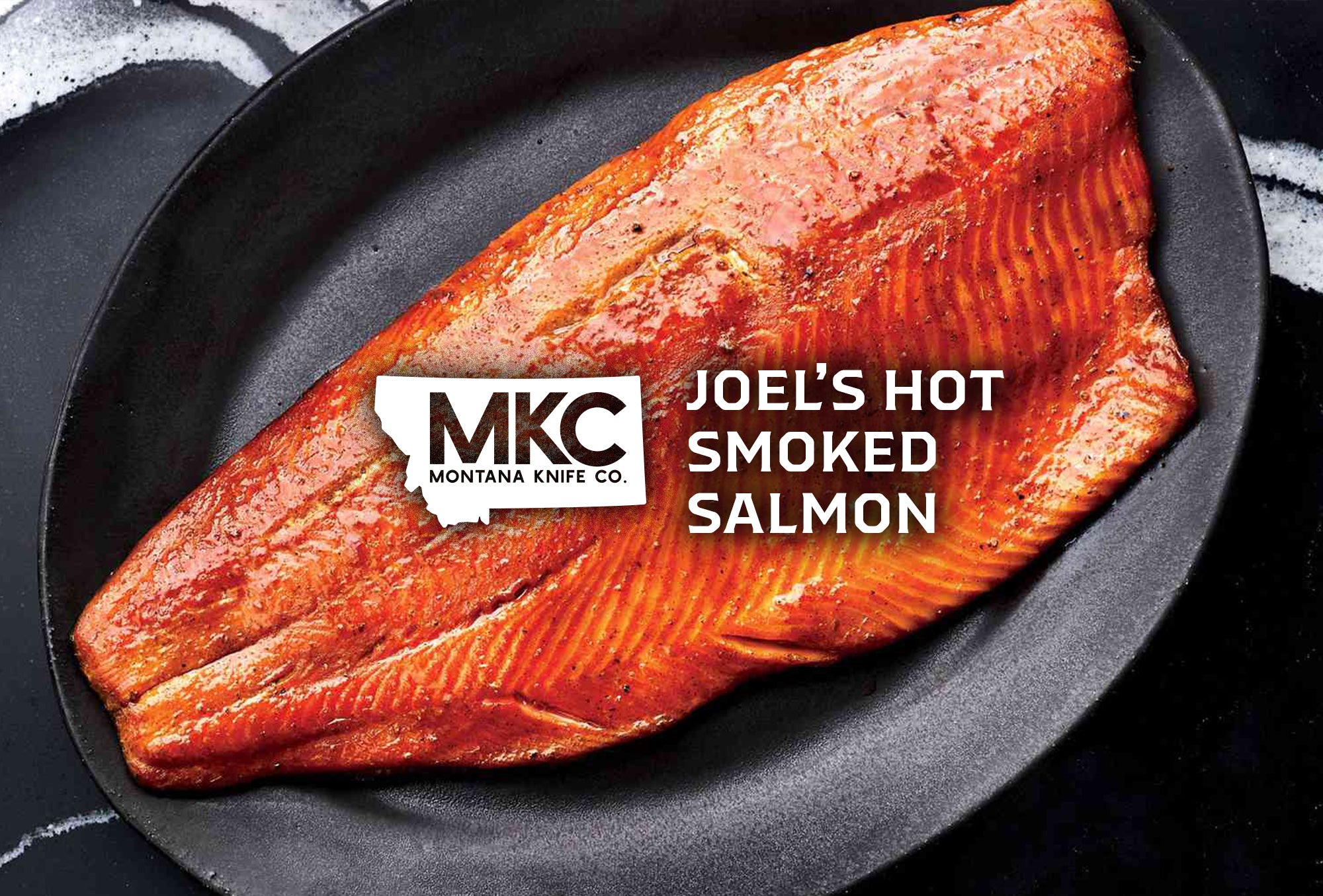A large, hot smoked salmon filet rests in a clean cast iron pan.