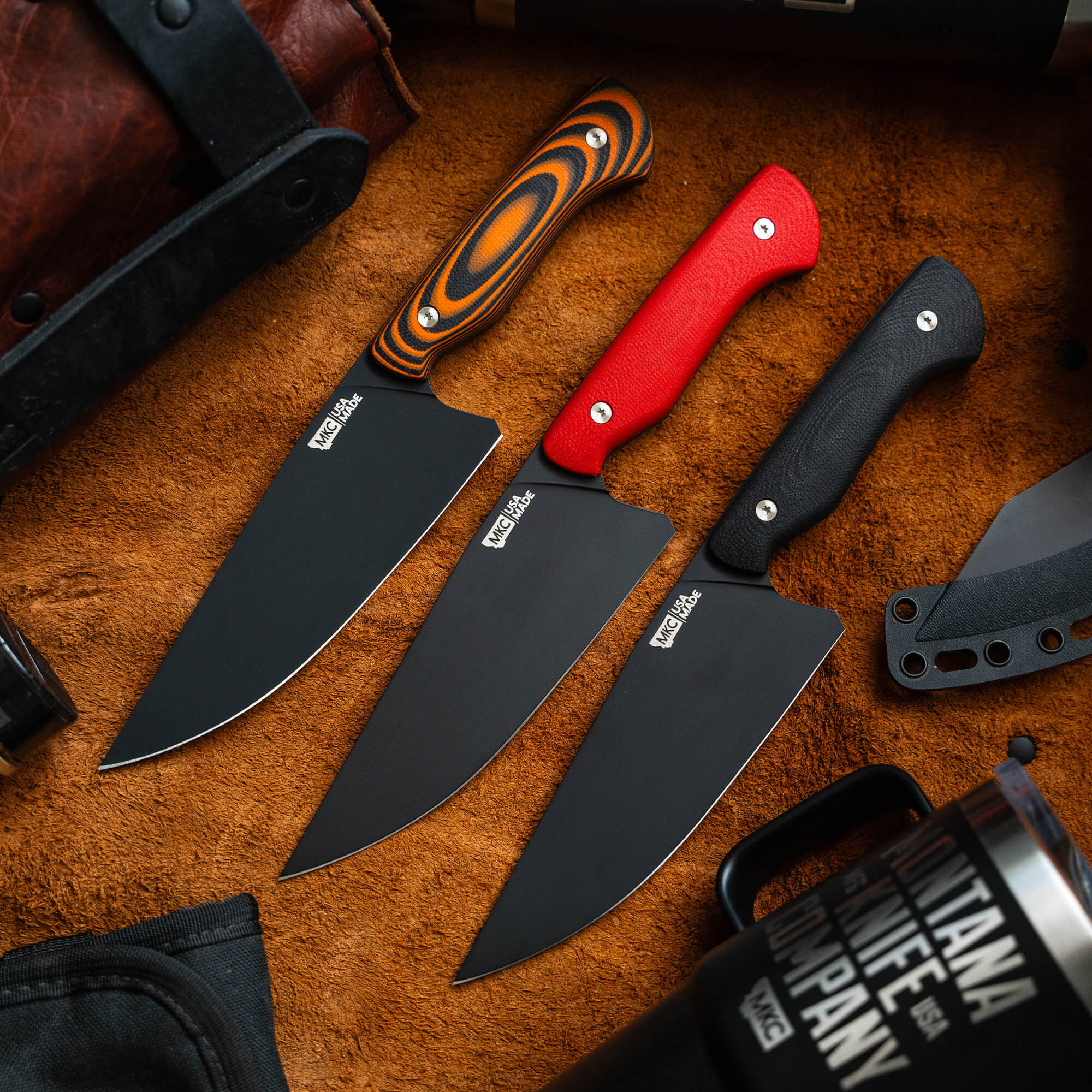 A collection of Meat Church chef knives with varied handle designs including striped orange, solid red, and textured black, displayed on a textured leather background. Each knife features a prominent black blade with the Meat Church logo.